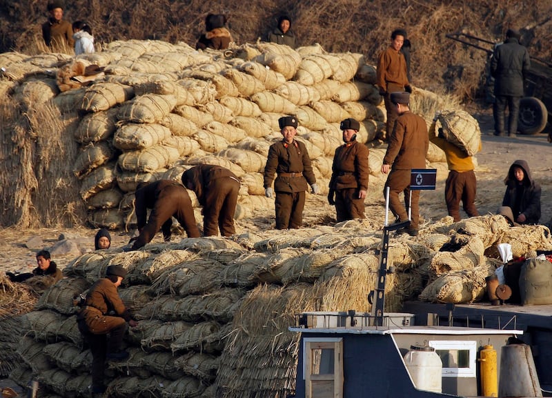 북한 군인들이 신의주 인근 압록강 제방에 정박한 화물선에서 쌀 포대를 내리고 있다.