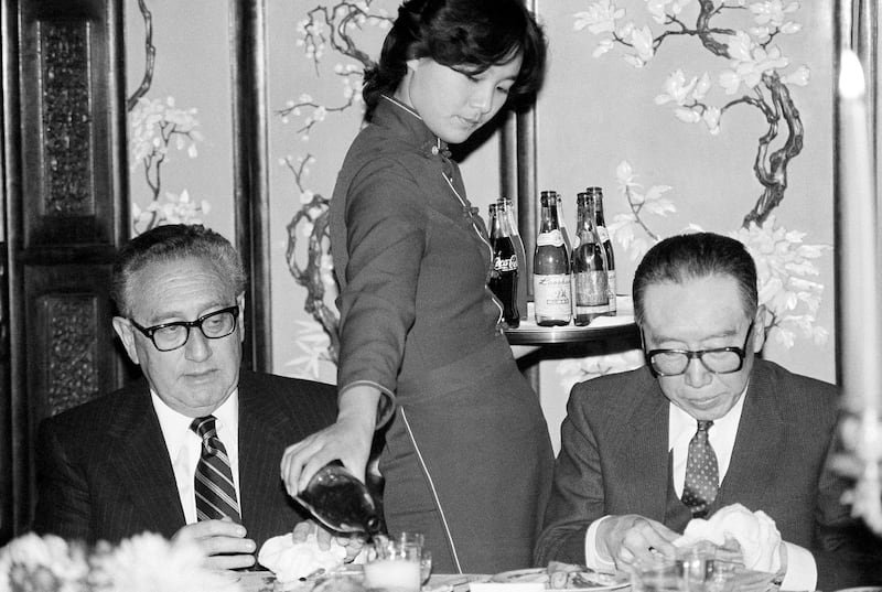 A waitress pours a drink for former Secretary of State Henry Kissinger at a banquet in Beijing in his honor, Nov. 9, 1985. (Neal Ulevich/AP)