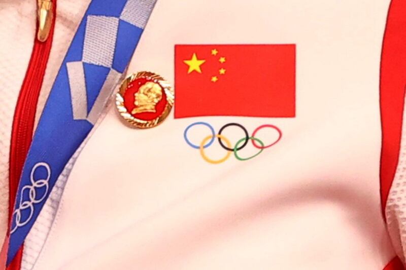 A badge of Mao Zedong, next to China's national flag and the Olympic symbol, on the uniform of a Chinese women's team member at the at the Women's Team Sprint medal ceremony in Shizuoka, Japan, Aug. 2, 2021. Credit: Reuters