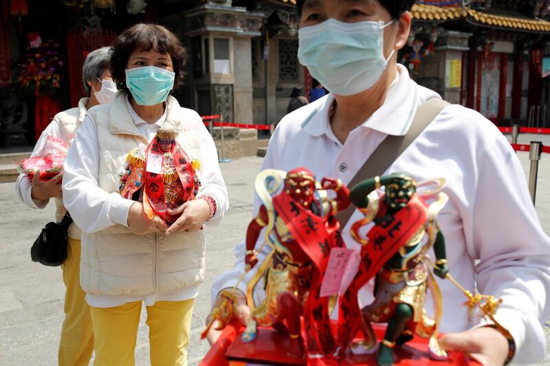 2020年4月15日，在台湾云林北港朝天宫祈祷后，戴着口罩以保护自己免受冠状病毒 (COVID-19) 感染的信徒抬着中国海神妈祖的雕像。（路透社）