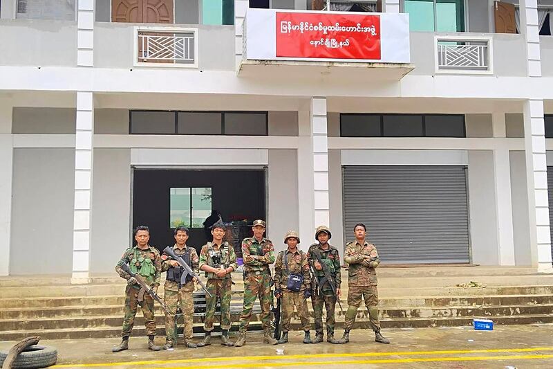 Members of the Ta'ang National Liberation Army and the Mandalay People's Defense Force stand in front of the captured building of the Myanmar War Veterans' Organization in Nawnghkio township in Shan state, June 26, 2024. (Mandalay People's Defence Force via AP)