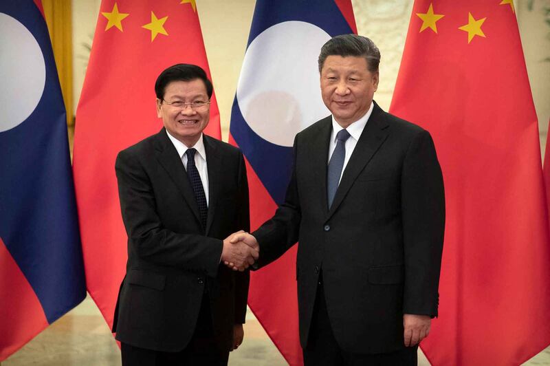 China's President Xi Jinping [right] shakes hands with Laos then-Prime Minister Thongloun Sisoulith before a meeting in Beijing on Jan. 6, 2020. Credit: Mark Schiefelbein/Pool via AFP