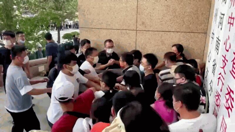 Plain-clothed security personnel scuffle with demonstrators during a protest over the freezing of deposits by some rural-based banks, outside a People's Bank of China building in Zhengzhou, Henan province, China, July 10, 2022. Credit: Screengrab via Reuters