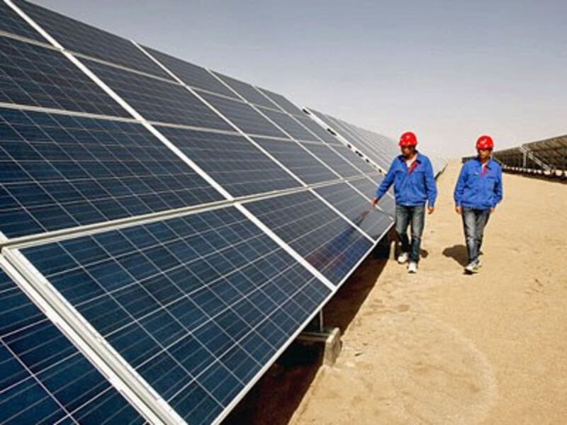 Chinese workers walk past arrays of solar panels at a solar power plant in northwestern China's Qinghai province in a file photo.