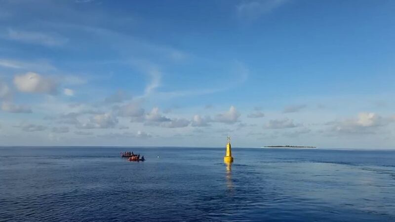 This screengrab from a video clip disseminated by the Philippine Coast Guard on May 20, 2022, shows coast guard personnel near a Filipino navigational buoy deployed in Manila-claimed waters in the South China Sea. Credit: Philippine Coast Guard.