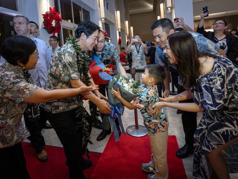 Taiwan's President Lai Ching-te, center, receives a bouquet of flowers from a young boy as he is greeted by members of local Taiwanese community in Tumon, Guam, Dec. 4, 2024.