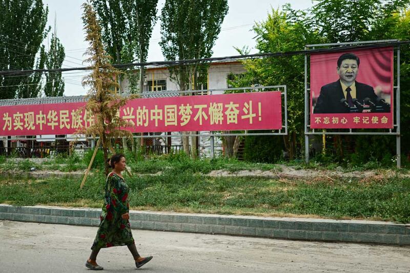 A woman passes by a portrait of Chinese President Xi Jinping accompanied by a propaganda slogan urging people to "struggle unremittingly to realize the Chinese dream of the great rejuvenation of the Chinese people", near Yarkant in northwestern China's Xinjiang region. Credit: Pedro PARDO / AFP