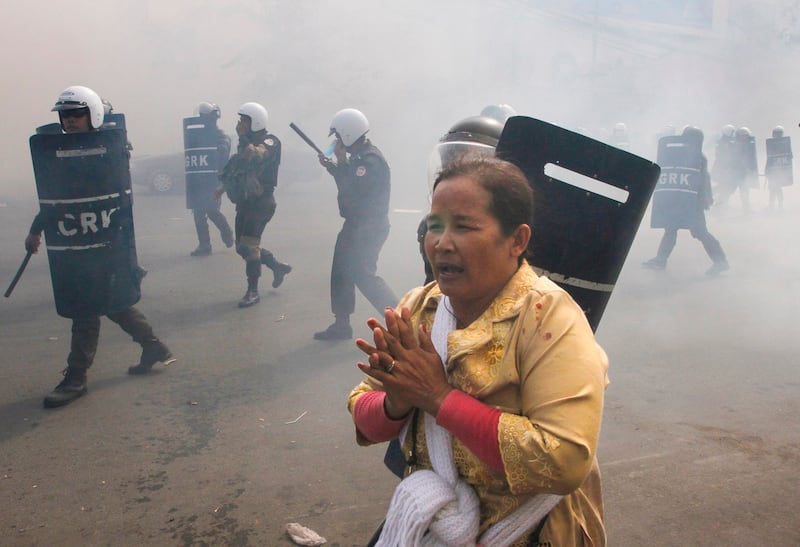 A protester, center, escapes from riot police officers who fire tear gas grenades during a protest in Phnom Penh, Cambodia, Jan. 27, 2014. (Heng Sinith/AP)