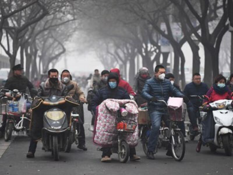 Scooter riders wait to cross a road on a heavily polluted day in Shijiazhuang, northern China's Hebei province, Dec. 21, 2016.