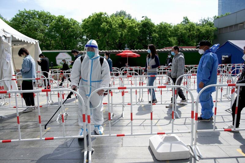 A worker disinfects the queue area of a swab test collection site for Covid-19 coronavirus in Beijing, May 11, 2022. Credit: AFP.