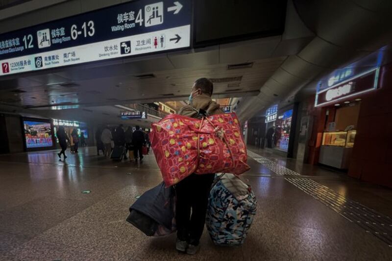 A Chinese migrant worker carries his belongings at the West Railway Station in Beijing, Jan. 6, 2023. (Wayne Zhang/AP)