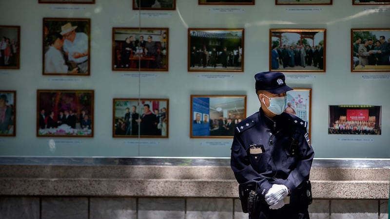 2020年4月21日，一名中国警察站在朝鲜驻北京大使馆外的朝鲜领导人照片展示前。（美联社）