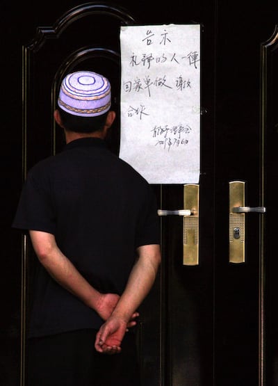 A Muslim man reads a sign attached to the entrance of a mosque telling worshipers to 'go home and pray there' in Urumqi, capital of northwestern China's Xinjiang Uyghur Autonomous Region, in a file photo. Credit: Reuters