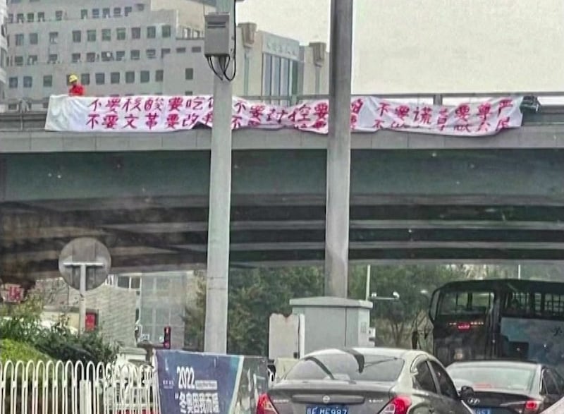 A protester hangs two banners off a Beijing overpass on Oct. 13, 2022. Credit: Screenshot from Reuters video