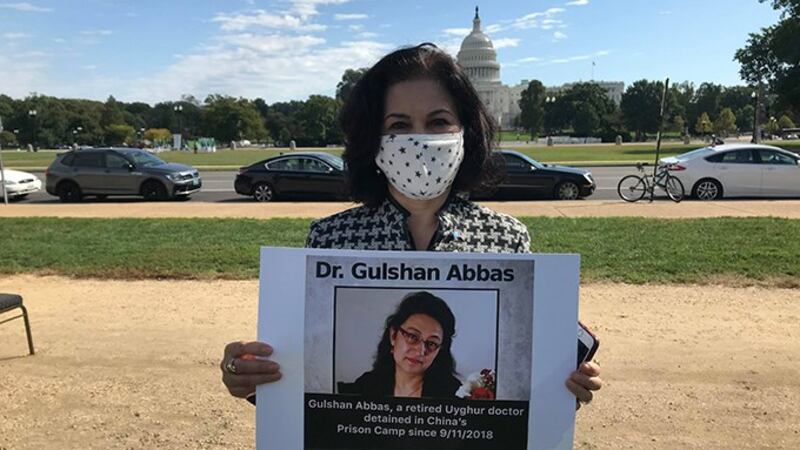 美国维吾尔活动人士罗珊•阿巴斯(Rushan Abbas)手持失踪姐妹的照片（视频截图）