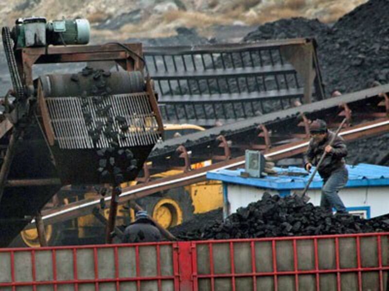 Chinese workers shovel coal as a conveyor loads it into a trailer truck at a coal mine near Ordos in northern China's Inner Mongolia Autonomous Region, Nov. 3, 2015.