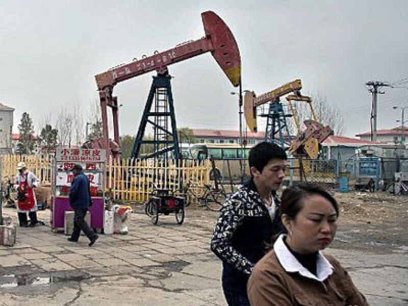 Chinese locals walk beside oil pumps in Daqing, northeastern China's Heilongjiang province, May 2, 2016. 