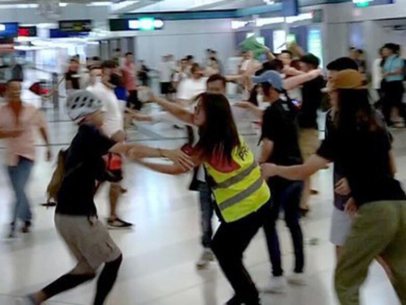 Wearing a cycle helmet, Galileo, a pseudonym, left, tries to protect Stand journalist Gwyneth Ho, right, during attacks by thugs at Yuen Long MTR, July 21, 2019 in Hong Kong.