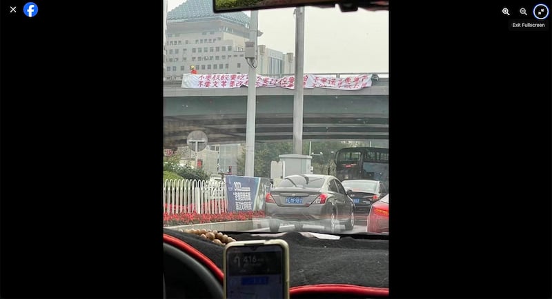 Peng Lifa, seen on the bridge in orange at left, hangs two protest banners off Beijing's Sitong Bridge, Oct. 13, 2022. (Boycott Made In China via Facebook)