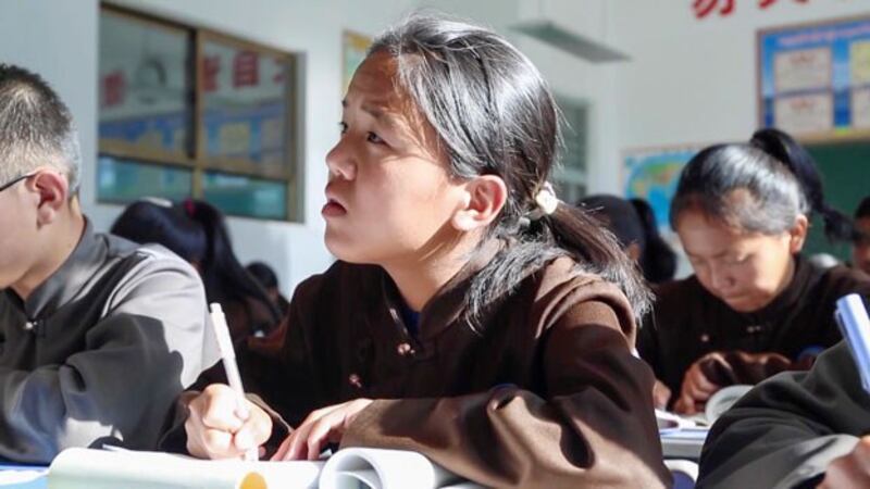 A student writes in a lesson book during a class at a boarding school in Tibet, Aug. 17, 2023. (China News Service via Reuters)