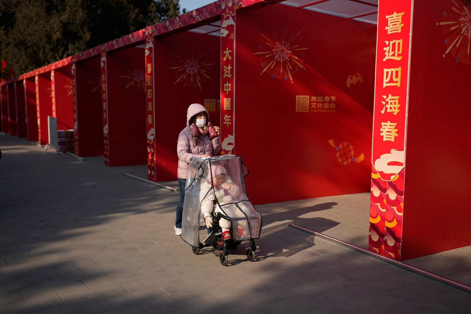 2025年1月22日，一名女子推着婴儿车，走过北京地坛公园准备迎接农历新年的空摊位。