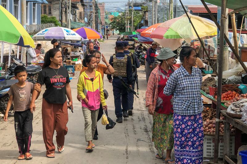 Armed police walking past people at a market area in Lashio in Myanmar's northern Shan state on Sept. 10, 2024, after the Myanmar National Democratic Alliance Army (MNDAA) seized the town from Myanmar's military in August. (AFP Photo)