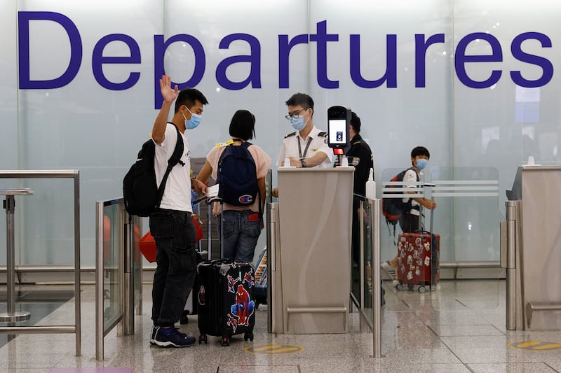 A man waves to family members before leaving for the United Kingdom at the Hong Kong International Airport, June 30, 2021. (Tyrone Siu/Reuters)