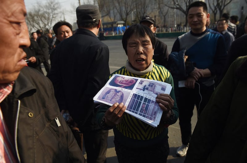 A petitioner holds photos of evidence in her grievance against local officials, outside a government petition office in Beijing on March 2, 2016, a few days before the National People's Congress opens its annual session. (Greg Baker/AFP)