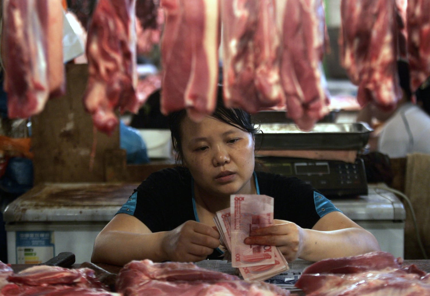 资料照：重庆市的一名猪肉摊贩在市场上清点人民币。