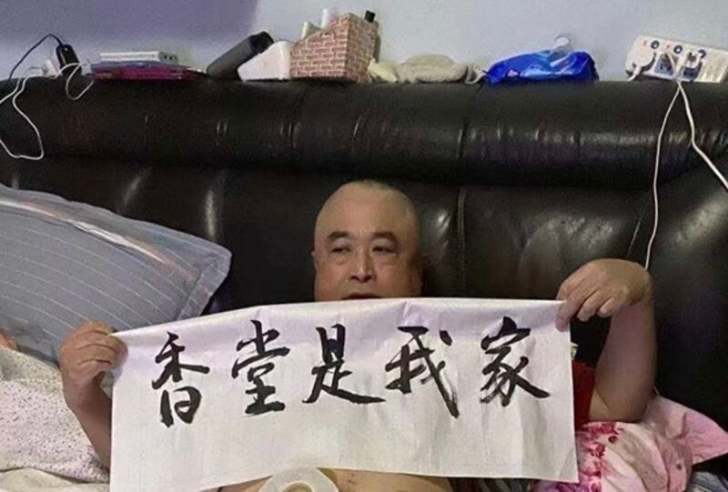 一名卧病在床的老人在家中举起横幅“香堂是我家”，表示对强拆的抗议。（小区业主提供，独家首发）