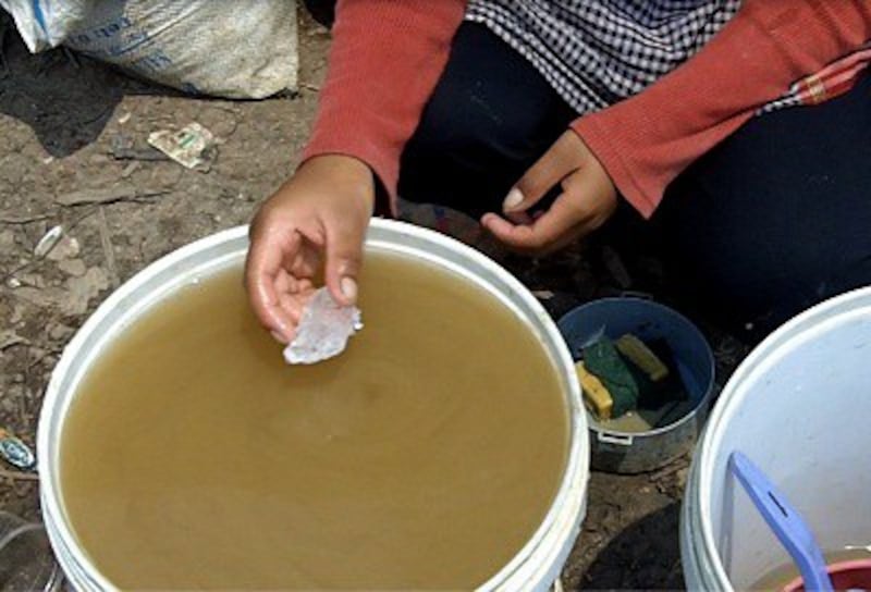 A Peam Ta Our woman uses chemicals to treat brown water from the Tonle Sap. Photo credit: RFA.