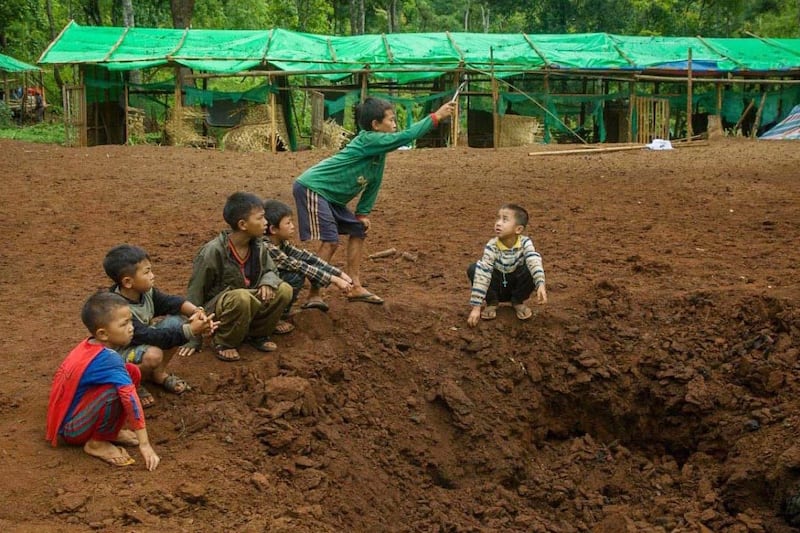 Children sit at the crater caused by a bomb explosion, after an aerial attack on an IDP camp in western part of Demoso, Kayah state, Myanmar, June 4, 2023.