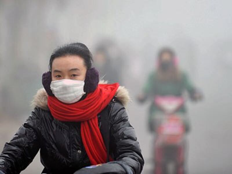 A woman rides a bike in heavy smog along a street in Haozhou, central China's Anhui province, Jan. 30, 2013.