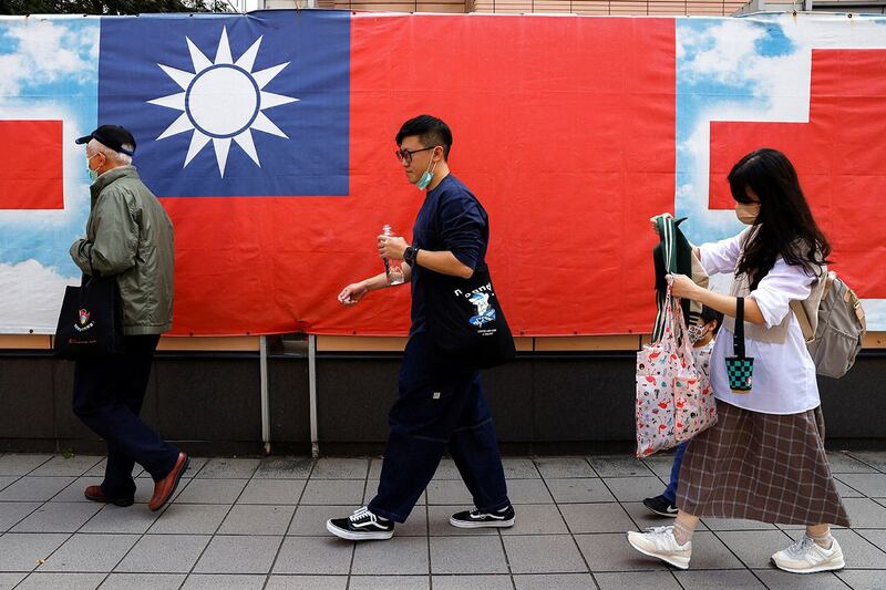 人们从台北街头的台湾旗帜旁走过（路透社）