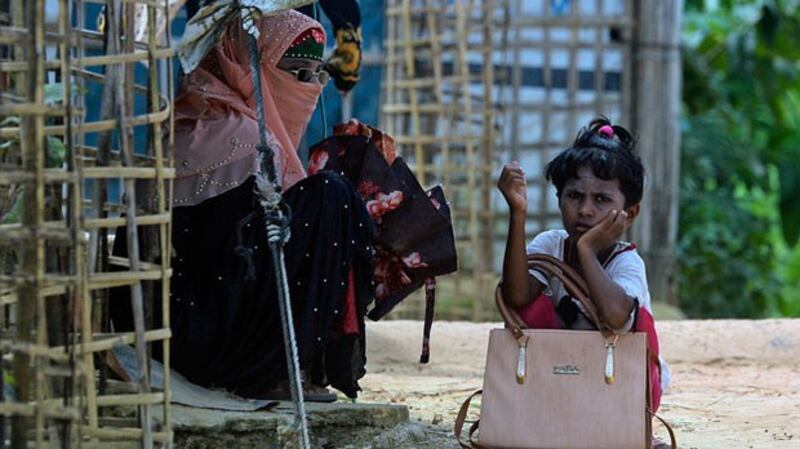 A Rohingya refugee girl waits for transportation with her mother at the Kutupalong refugee camp in Ukhia, Cox's Bazar district, southeastern Bangladesh, Oct. 15, 2020.