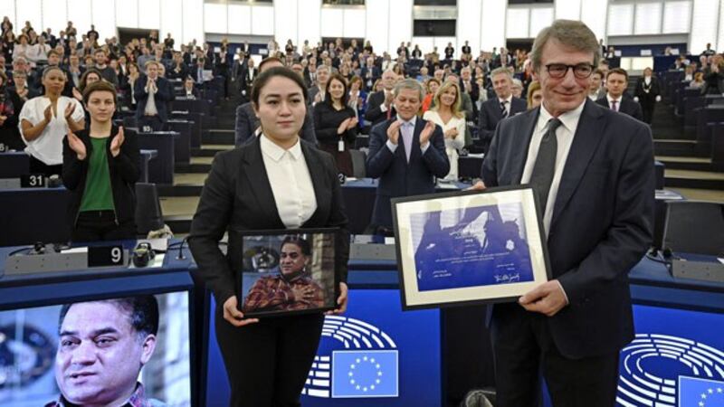 Lawmakers applaud as European Parliament President David-Maria Sassoli (R) stands next to Jewher Ilham (L), daughter of Uyghur economist and human rights activist Ilham Tohti, as she holds a photo of her father during the award ceremony for the 2019 Sakharov Prize at the European Parliament in Strasbourg, eastern France, Dec. 18, 2019.