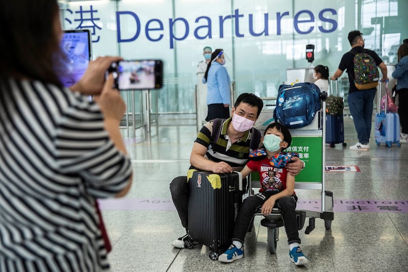 This picture taken on July 19, 2021, shows a family taking a photo at the departure gates of Hong Kong's International Airport before they emigrate to Britain.