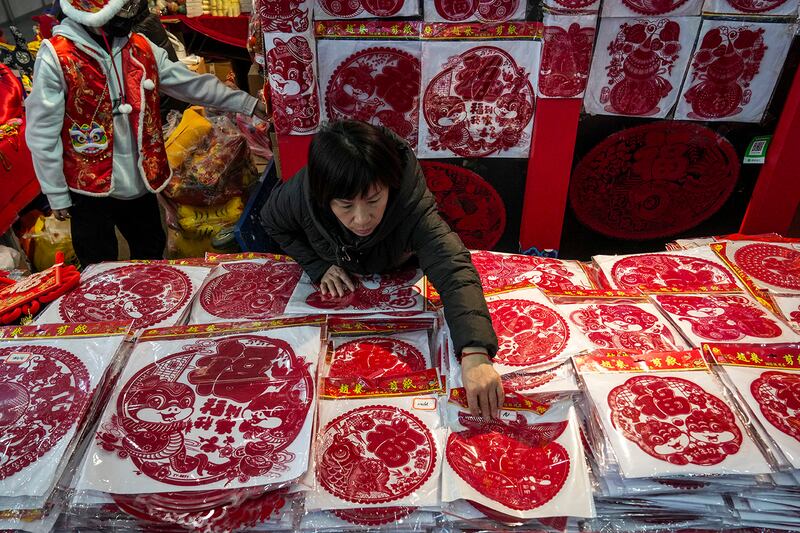 A vendor arranges prosperity decorations at her booth at a New Year bazaar in Beijing, Jan. 13, 2025.