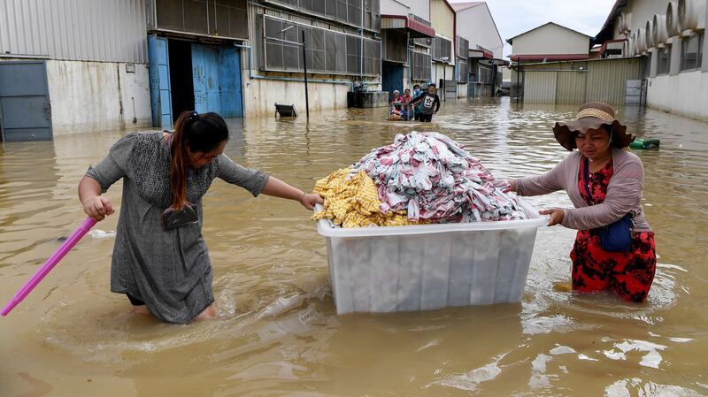 Workers salvage clothes from a factory through floodwaters on the outskirts of Phnom Penh, Oct. 18, 2020.