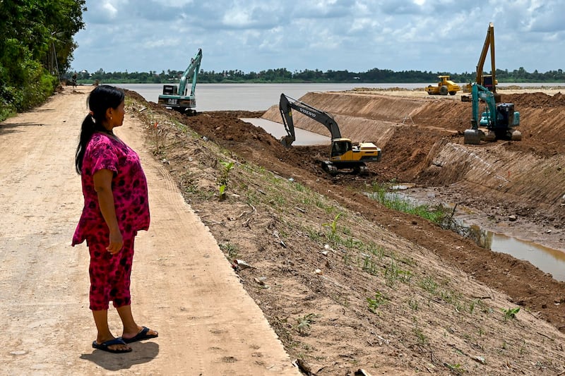 Villager Sok Rom looks at excavators being used on the construction of the Funan Techo canal along the Prek Takeo channel in Kandal province, July 9, 2024. (Tang Chhin Sothy/AFP)