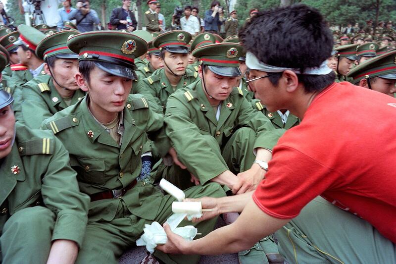 1989年5月15日，北京，罢工的学生向人民大会堂前的解放军士兵提供冰淇淋。当时杨尚昆正与苏联领导人戈尔巴乔夫会谈。（法新社）