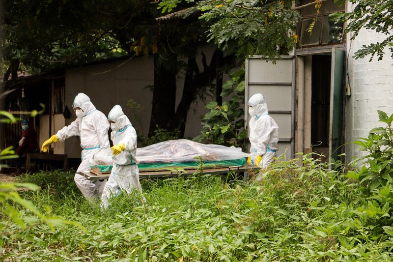 This photo taken and received courtesy of an anonymous source via Facebook on July 6, 2021 shows volunteers wearing personal protective equipment (PPE) carrying a body of a Covid-19 coronavirus victim for burial at Myoma Cemetery in Yangon, amid a surge in cases in the country. HANDOUT / FACEBOOK / AFP