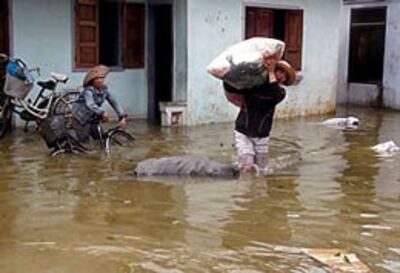 Người dân di chuyển đồ đạc do lũ tràn về tại Qui Nhơn, Bình Định hôm 16/11/2013. AFP