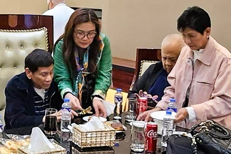 Former Philippine President Rodrigo Duterte, left, sits inside Villamor Air Base in Pasay, after arriving from Hong Kong, March 11, 2025.