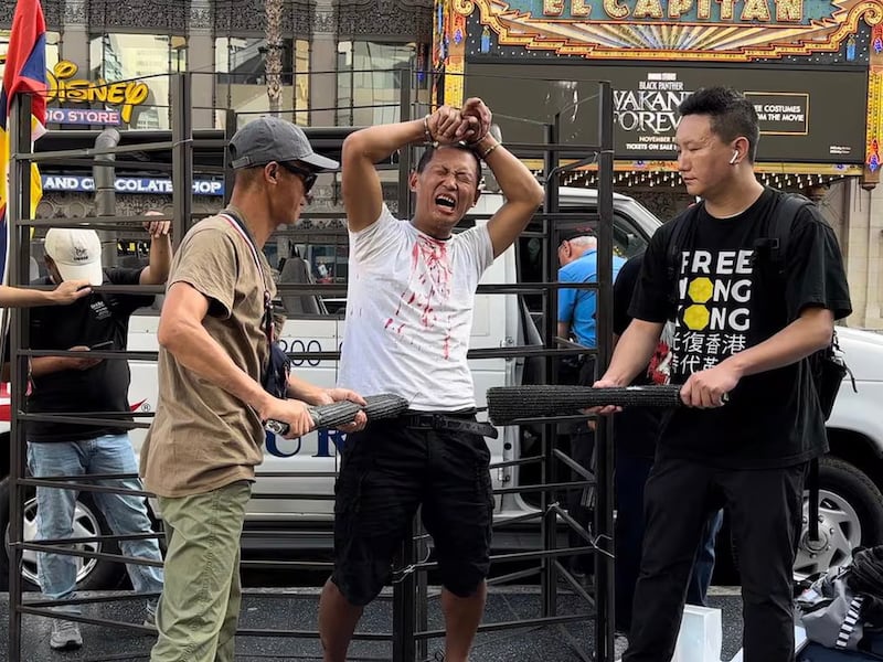 U.S.-based former forced psychiatric inmate Jie Lijian demonstrates torture he underwent in a Chinese psychiatric hospital, during a street display in Hollywood, California, Oct. 9, 2022.