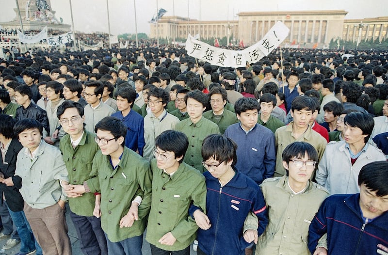 Chinese students link arms in solidarity at dawn on April 22, 1989 in Beijing's Tiananmen Square after spending the night there in order to be on hand for memorial services for the late purged party chief Hu Yaobang. Credit: Sadayuki Mikami/AP