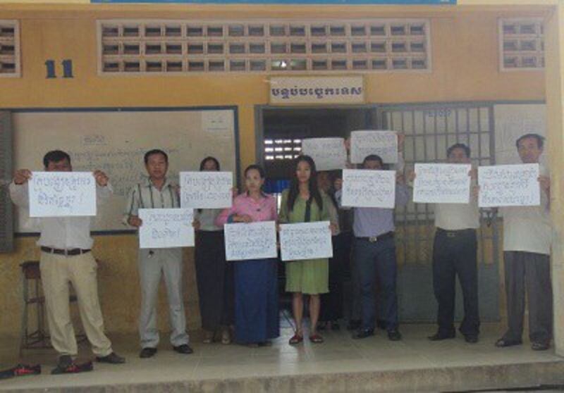 Striking Cambodian teachers display signs calling for higher salaries, Jan. 8, 2014.