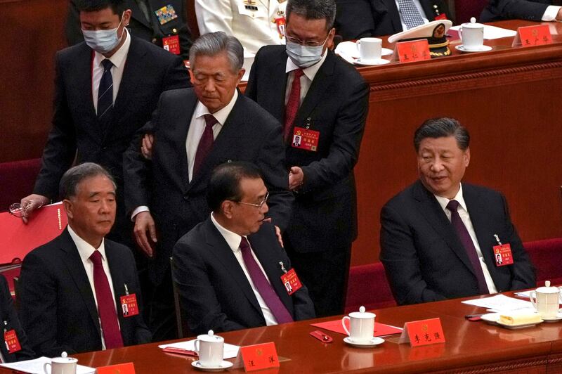 Chinese President Xi Jinping, right, looks on as former Chinese President Hu Jintao, standing at center, touches the shoulder of Premier Li Keqiang, center, as he is assisted to leave the hall during the closing ceremony of the 20th National Congress of China's ruling Communist Party at the Great Hall of the People in Beijing, Saturday, Oct. 22, 2022. (AP Photo/Andy Wong)