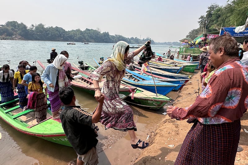 A woman jumps off a boat onto the riverbank at the annual Shwe Saryan Pagoda harvest festival in Shwe Saryan village, Patheingyi township, Mandalay region, Myanmar, March 11, 2025.