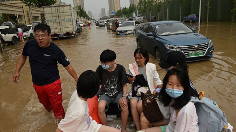 郑州居民在水灾期间乘坐橡皮艇通过被洪水淹没的街道（法新社）